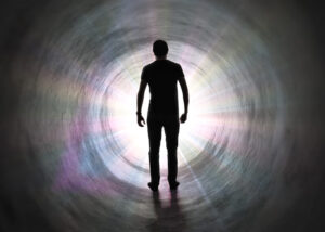 Life after death concept - Silhouette of man's soul is walking to bright light - rays of god inside tunnel